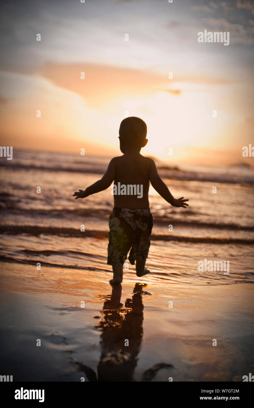 Young toddler running along a beach. Stock Photo