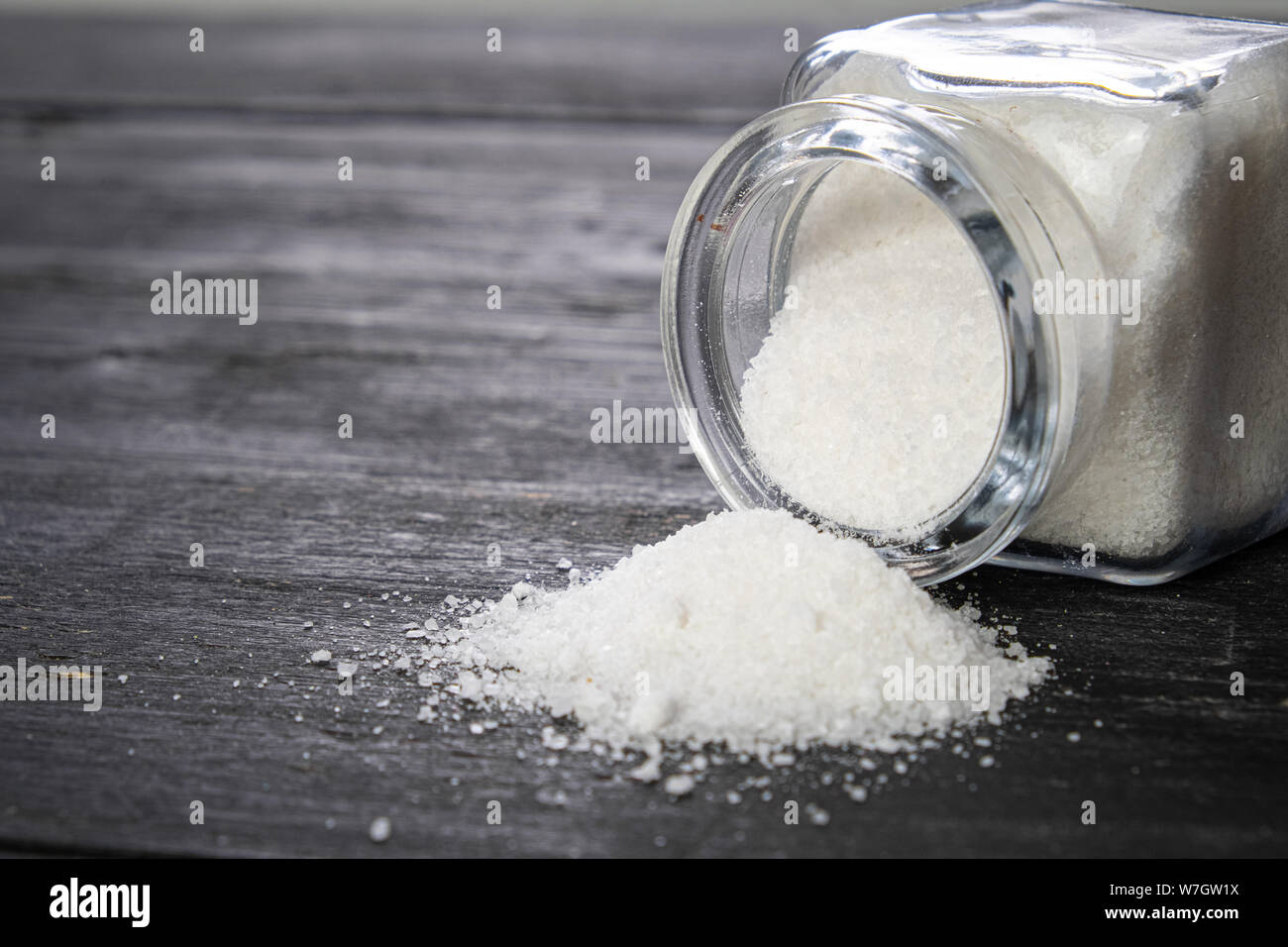 Sea salt in dark backfround, close-up view. Bunch of salt on dark wood table, concept of healthy nutrition concerns, eating habits. Stock Photo