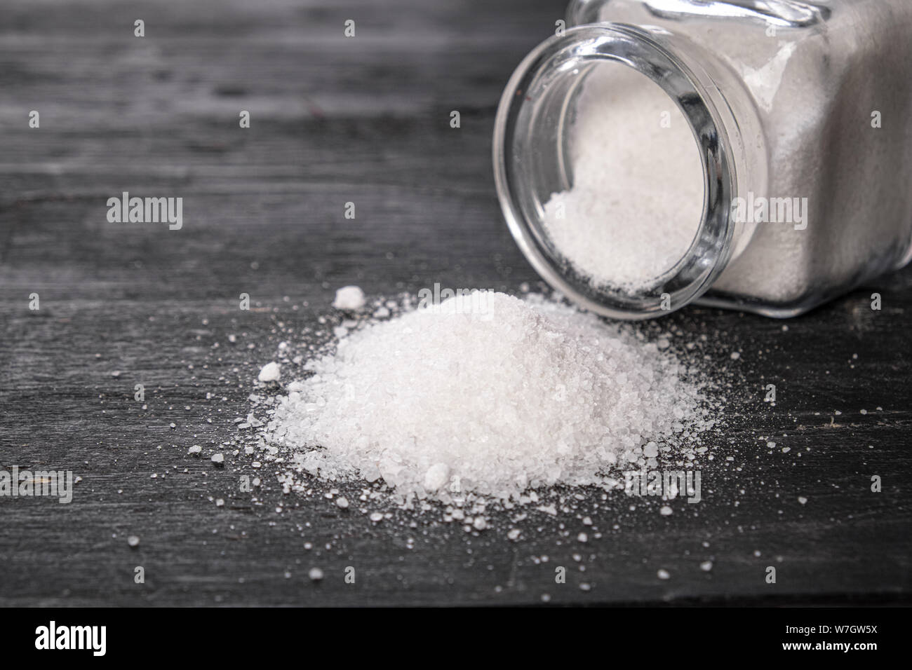 Sea salt in dark backfround, close-up view. Bunch of salt on dark wood table, concept of healthy nutrition concerns, eating habits. Stock Photo