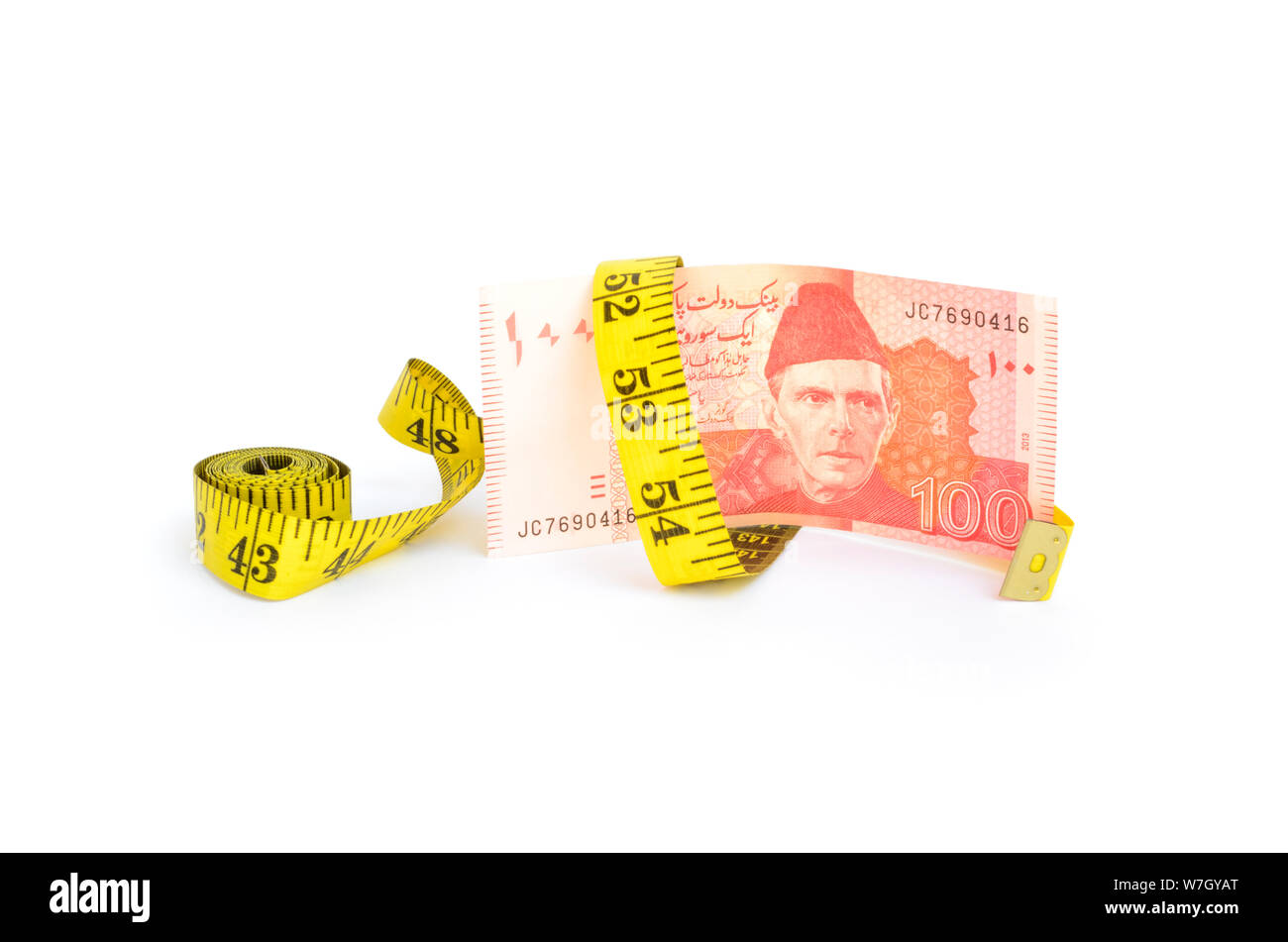 Closeup of hundred rupee Pakistani currency bill with measure tape for budget cut concepts Stock Photo