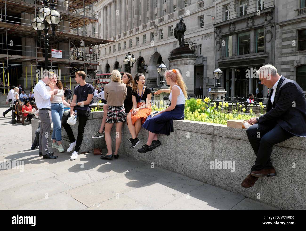 People in summer sitting at lunchtime in the square outside the Royal Exchange & Bank of England near Cornhill statue City of London UK  KATHY DEWITT Stock Photo