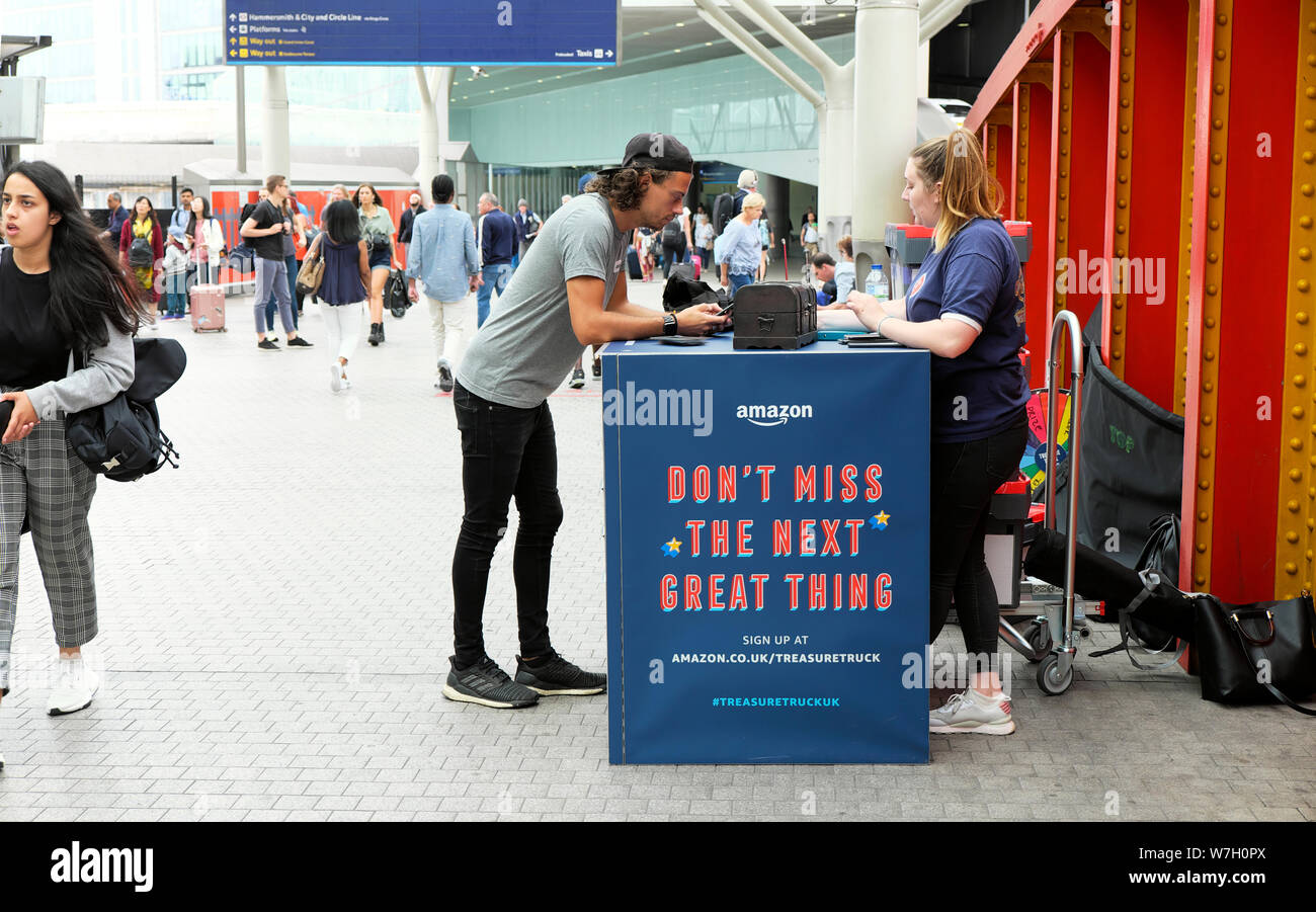 People at Amazon treasure truck kiosk with advert on the concourse at Paddington Station in West London England UK  KATHY DEWITT Stock Photo