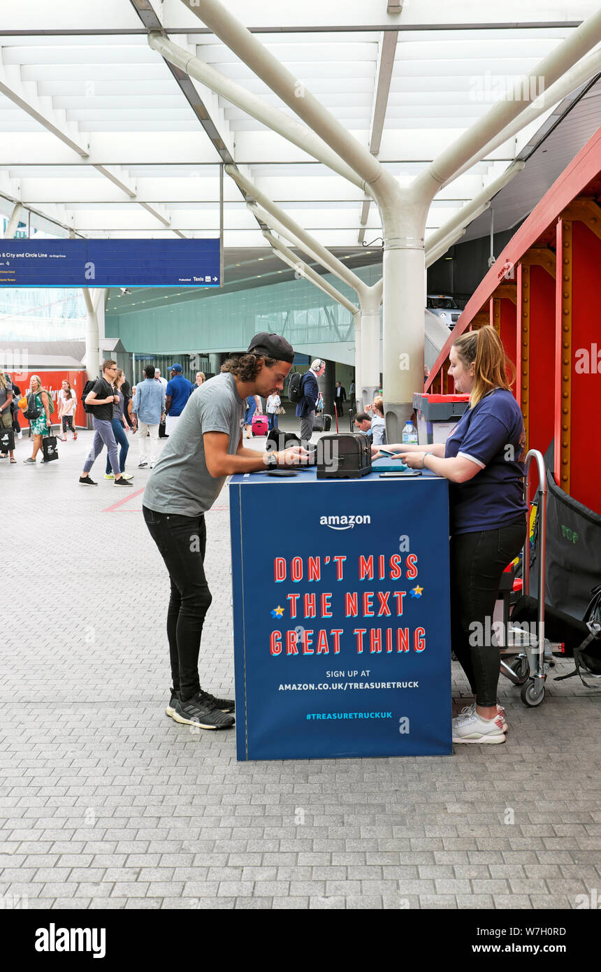 People at Amazon treasure truck kiosk with advert on the concourse at Paddington Station in West London England UK  KATHY DEWITT Stock Photo