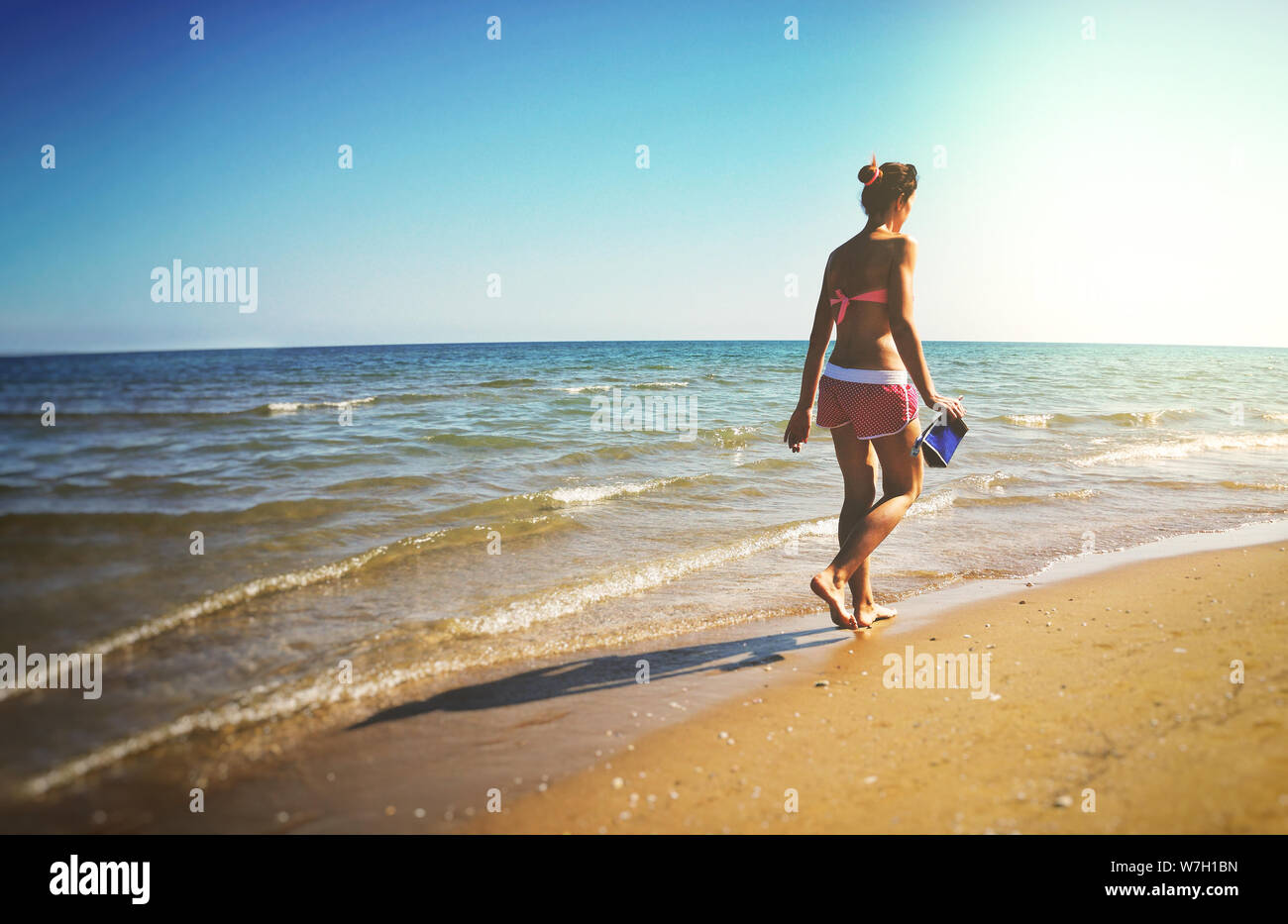 single woman walk beach from behind Stock Photo