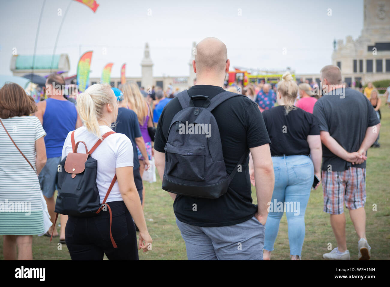 A couple wearing backpacks walking through a crowd at an outdoor festival Stock Photo