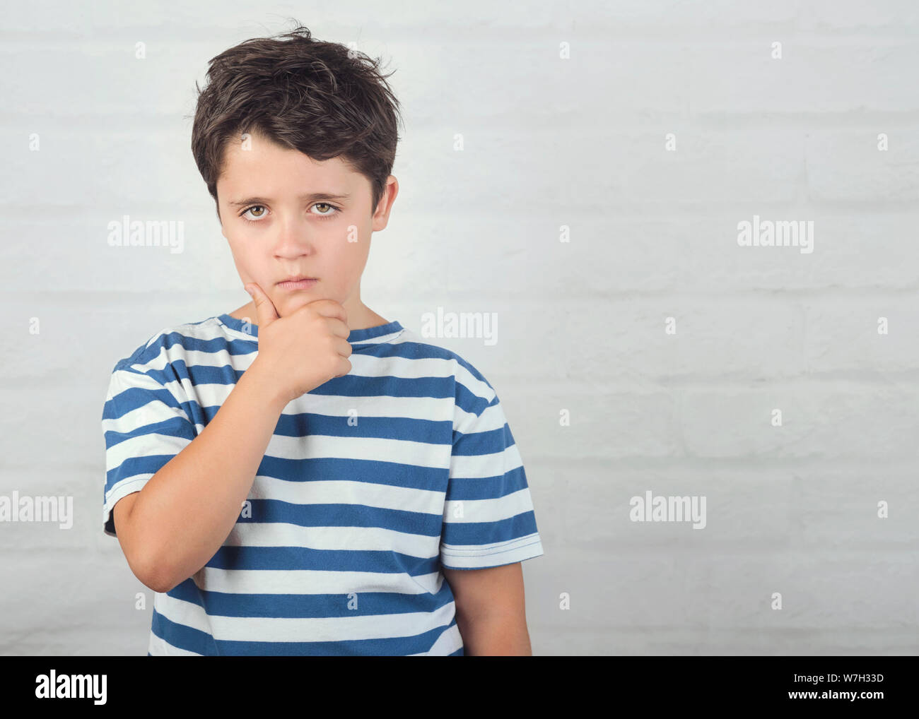 Portrait of serious boy against brick background Stock Photo