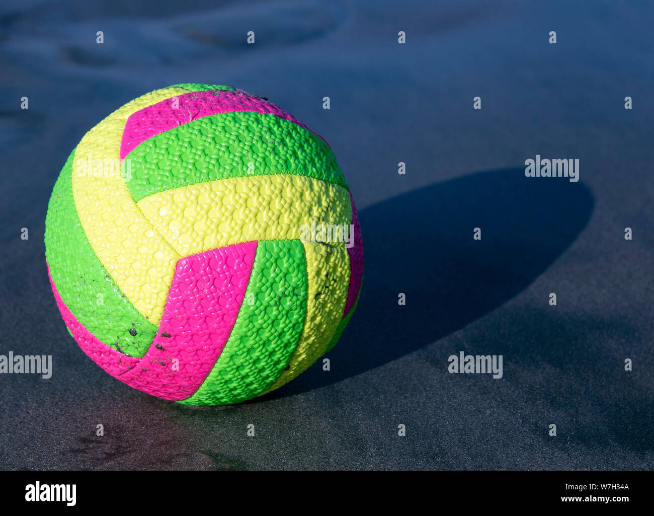 Bright multi-colored ball for beach volleyball on the sea dark sand. It ...