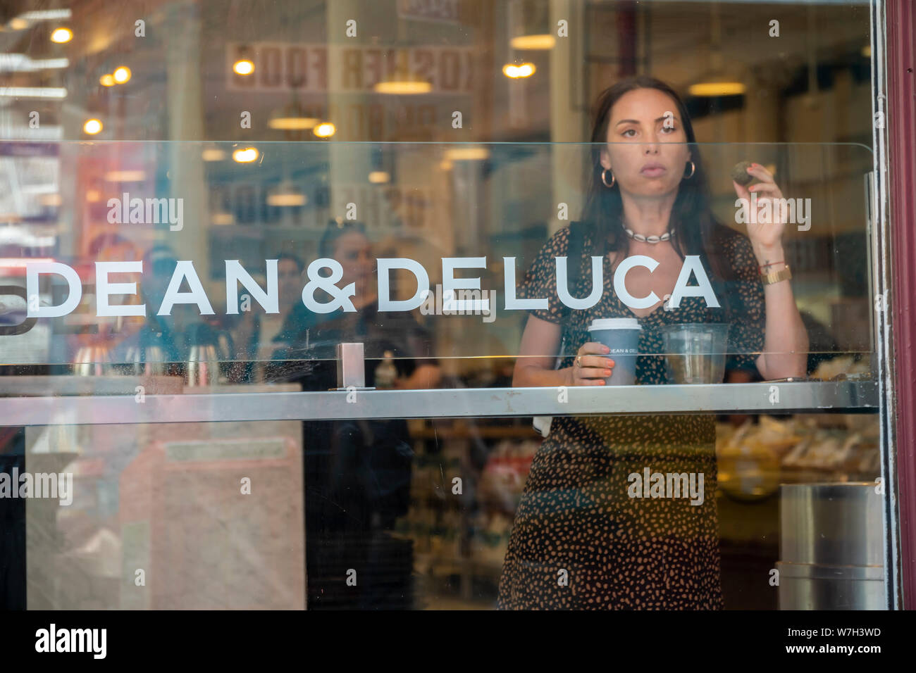 A woman has coffee in the window of the Dean & DeLuca store in Soho in New York on Saturday, August 3, 2019. Facing competition from a myriad of other sources the trail-blazing Dean & DeLuca has amassed a number of unpaid bills and is not being supplied by some of its vendors. (© Richard B. Levine) Stock Photo
