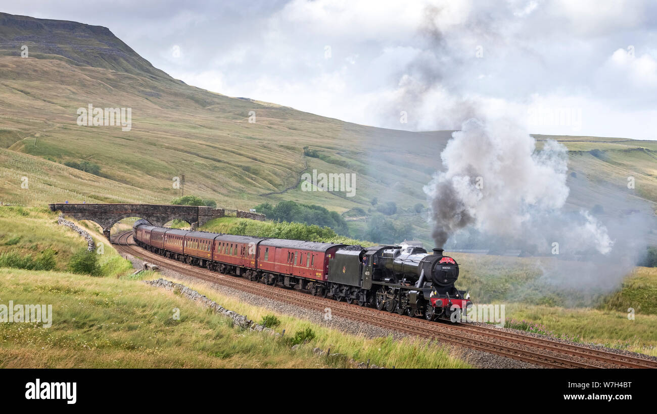 KIRKBY STEPHEN, CUMBRIA, UK. 6 AUGUST 2019 - LMS Stanier Class 8F No. 48151 climbs up Ais Gill, Cumbria, whilst hauling the 1Z56 Carlisle to Chester 'The Dalesman' charter train on the famous Settle & Carlisle railway line. Ais Gill, Cumbria, UK. 6th August 2019. Photograph by Richard Holmes. Credit: Richard Holmes/Alamy Live News Stock Photo