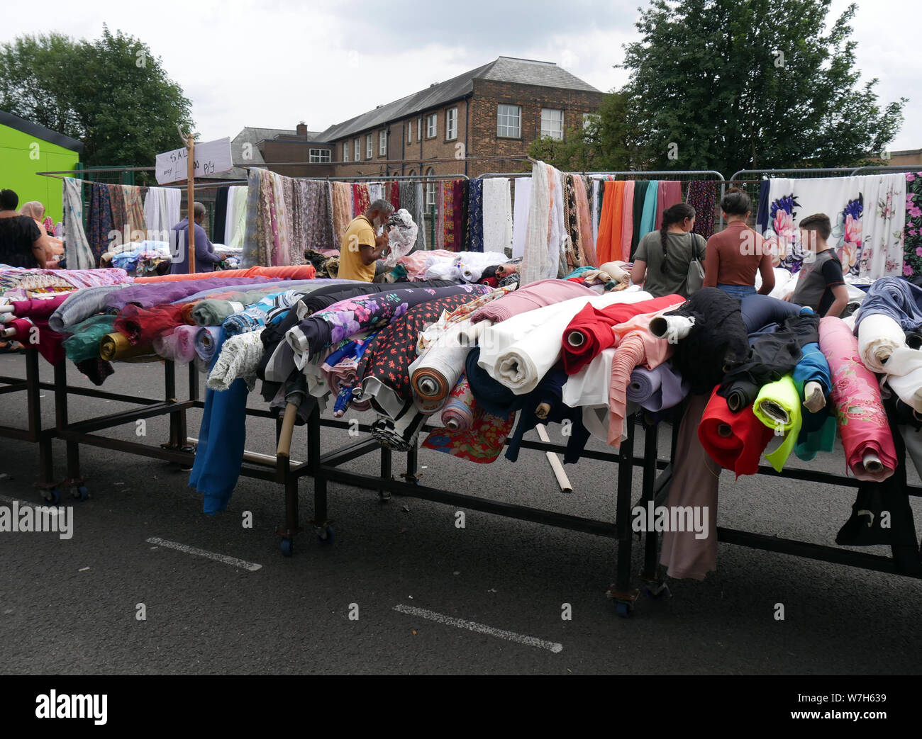 Asian shoppers looking at rolls of fabric & material while shopping on Bolton outdoor market in England UK.  photo DON TONGE Stock Photo