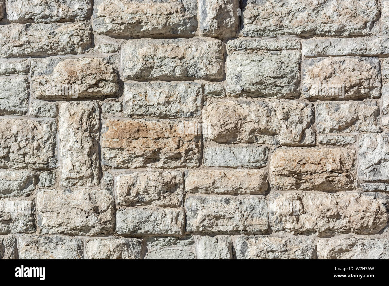 Dark fragment of an old limestone stone block wall for use as an abstract background and texture. Stock Photo