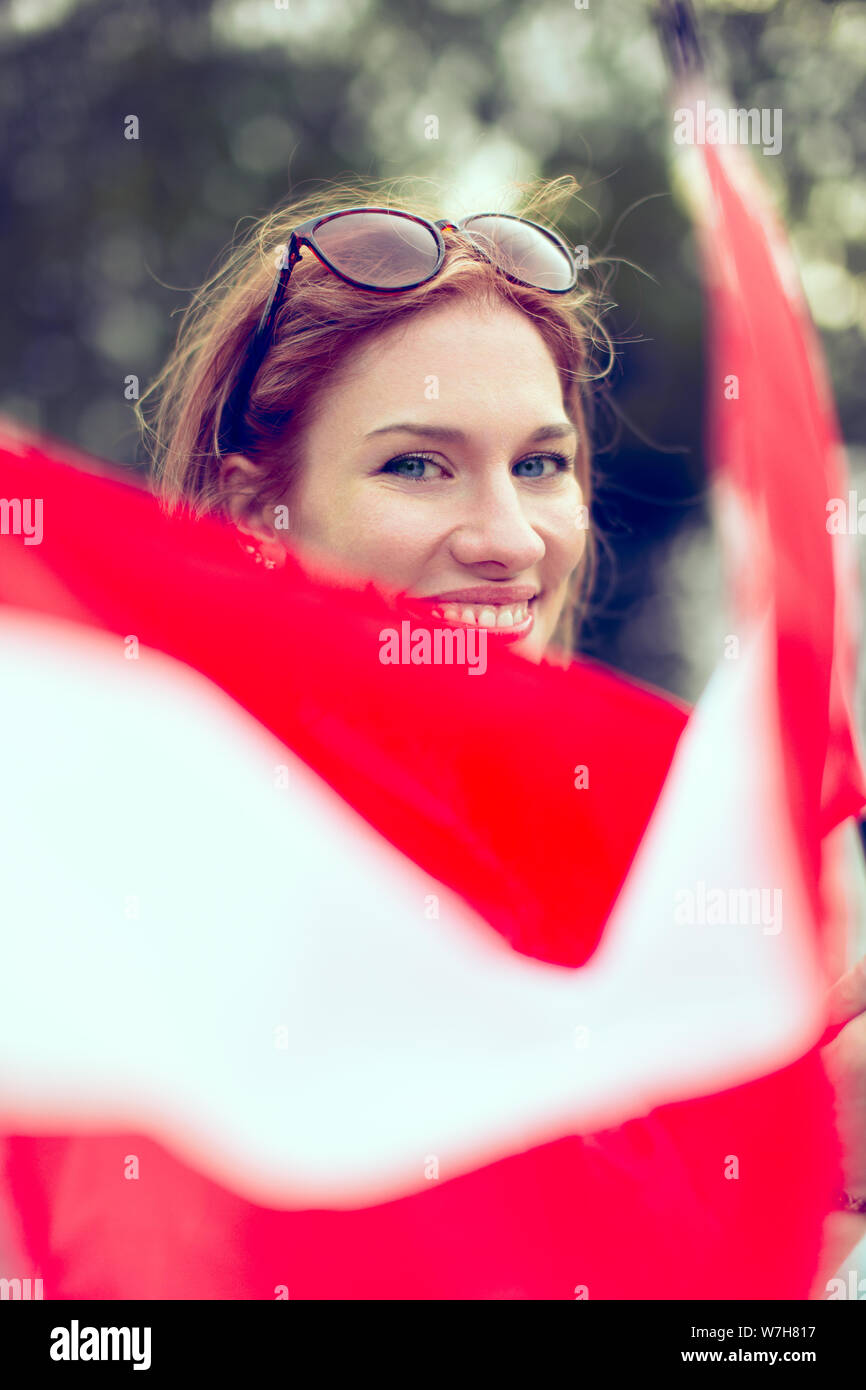 Happy young redhead woman waving Austrian flag closeup, depth of field, selective focus Stock Photo