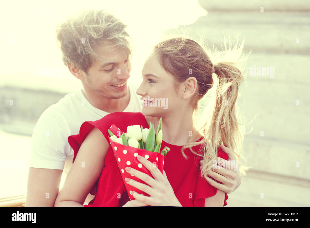 Man in love embracing woman with bouquet outdoors Stock Photo