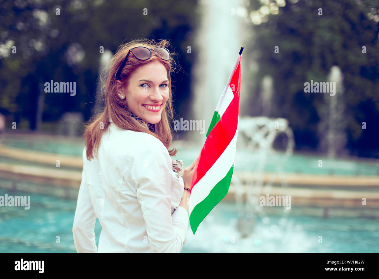 https://c8.alamy.com/comp/W7H82W/happy-young-woman-holding-hungarian-flag-at-fountain-looking-back-margaret-island-budapest-hungary-W7H82W.jpg