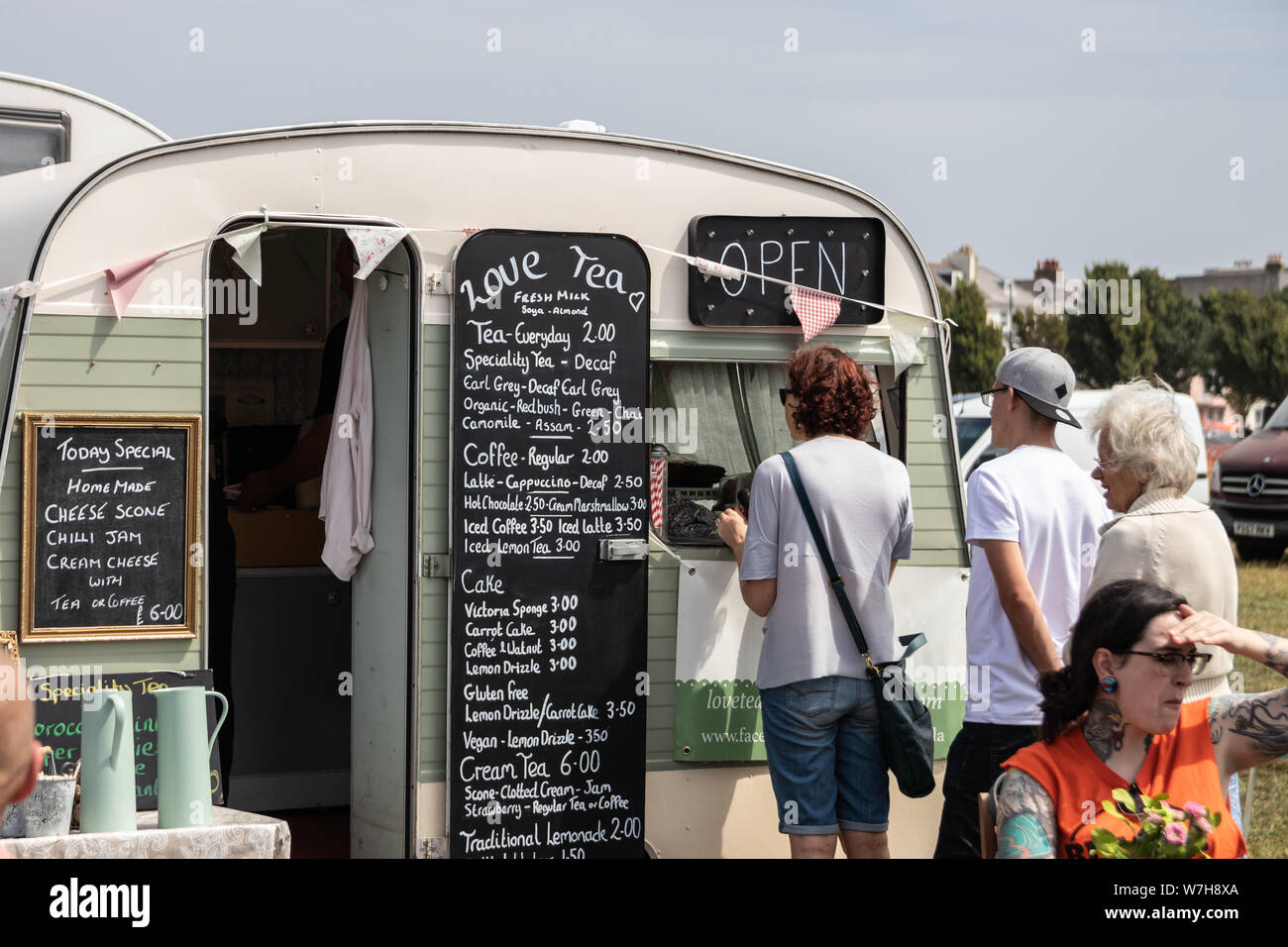 People queuing for tea and coffee at a vintage caravan converted into a mobile cafe Stock Photo