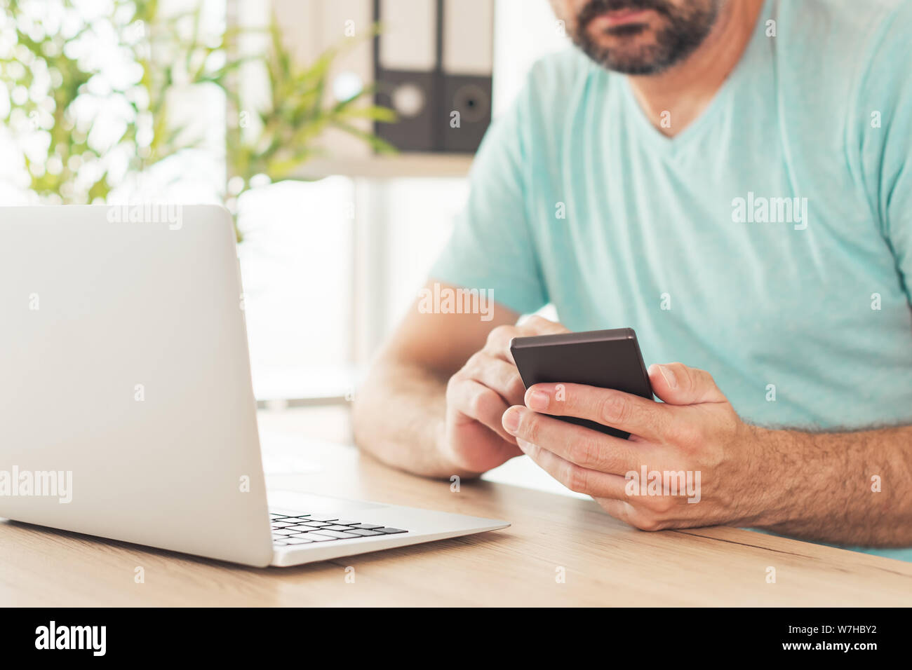 Two-step authentication and verification online internet account login concept. Casual adult caucasian freelancer man is using smartphone and laptop c Stock Photo