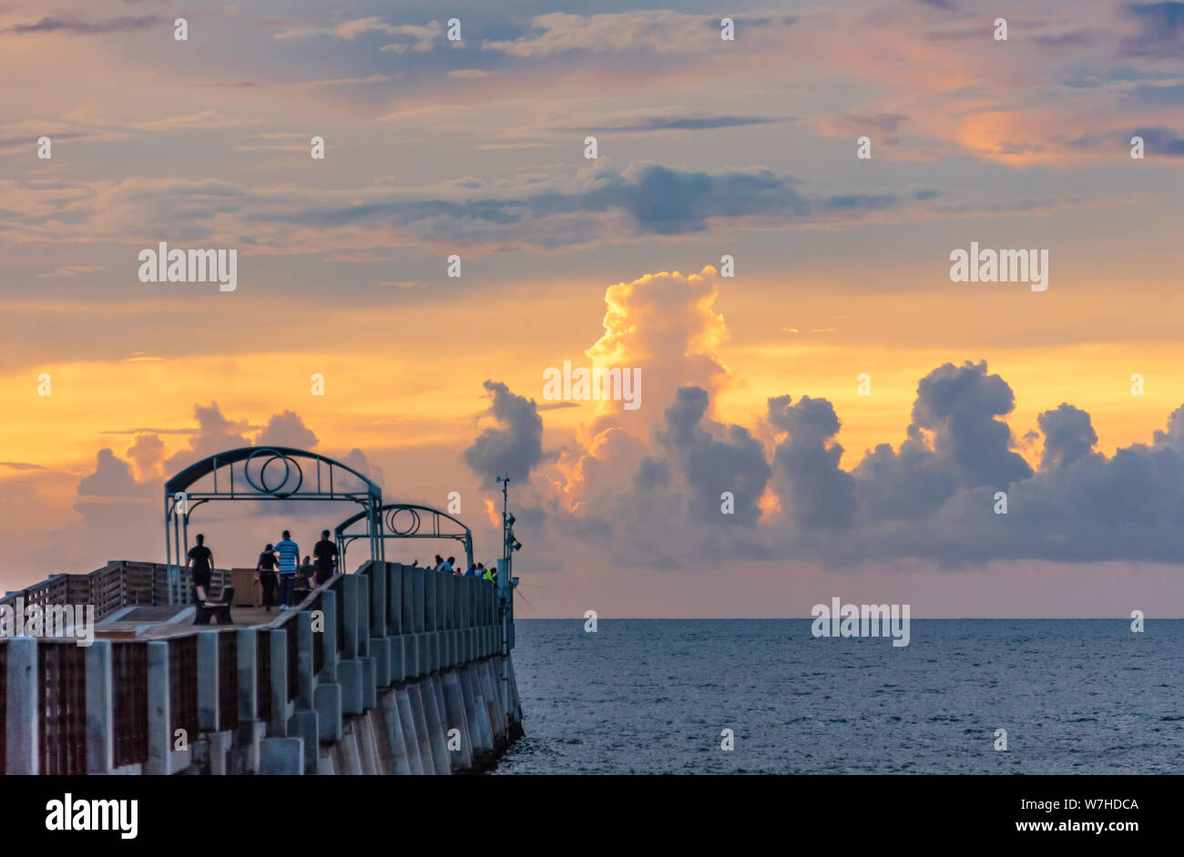 Colorful sunrise clouds adorn the horizon beyond Lake Worth Pier at Lake Worth Beach in Palm Beach County, Florida. (USA) Stock Photo