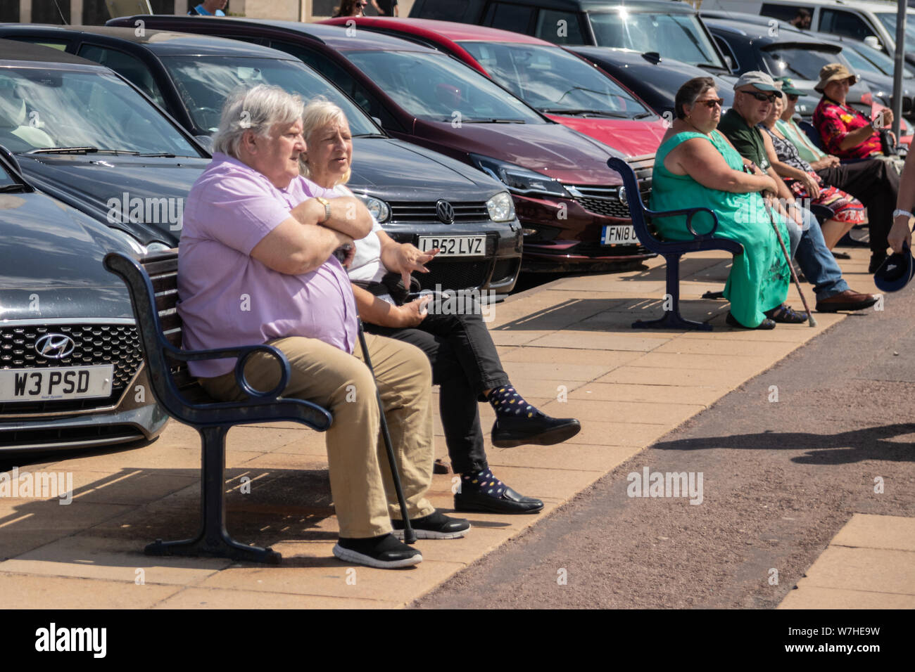A middle aged couple sat on a bench at the seaside Stock Photo