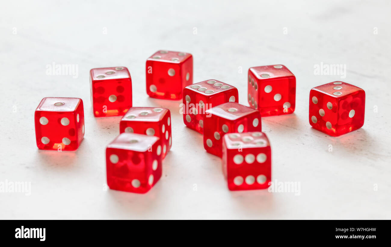 Ten red translucent craps dices on white board showing different numbers. Stock Photo