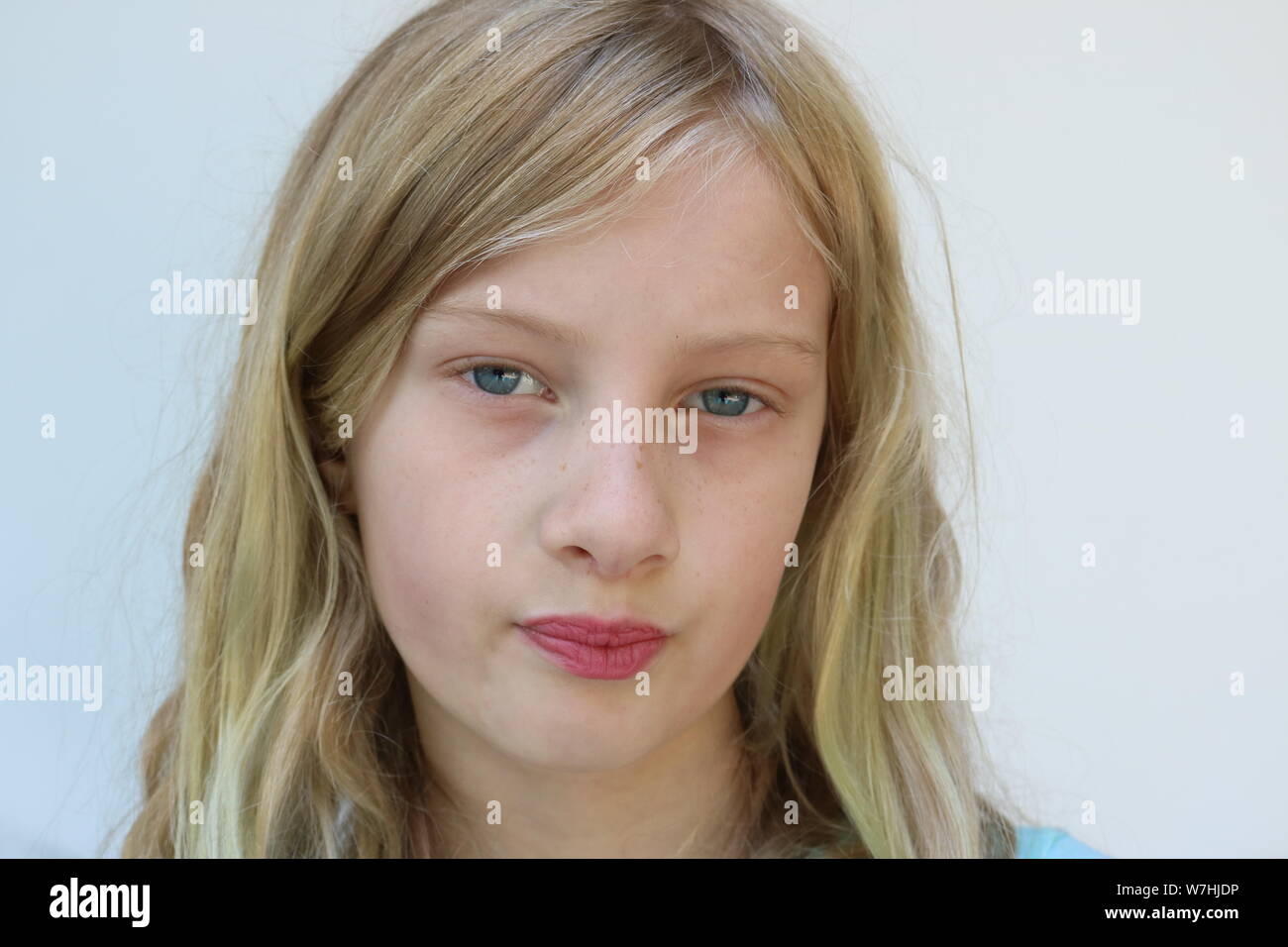 Portrait of a young blonde preteen with pursed lips and a defiant stare Stock Photo