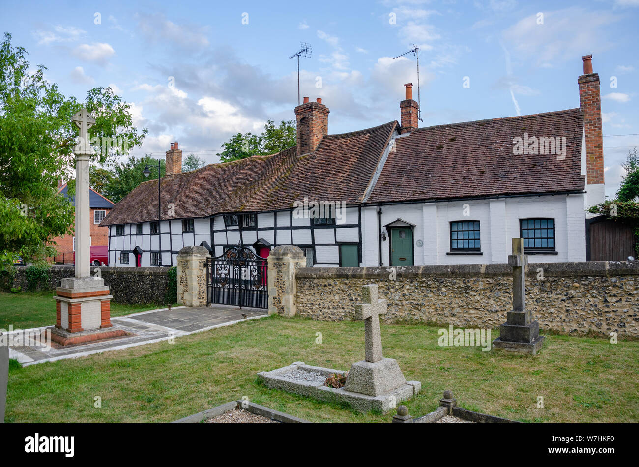 Half timbered black and white cottages in the village of Pangbourne in West Berkshire, UK beyond the churchyard of St James the Less Church. Stock Photo