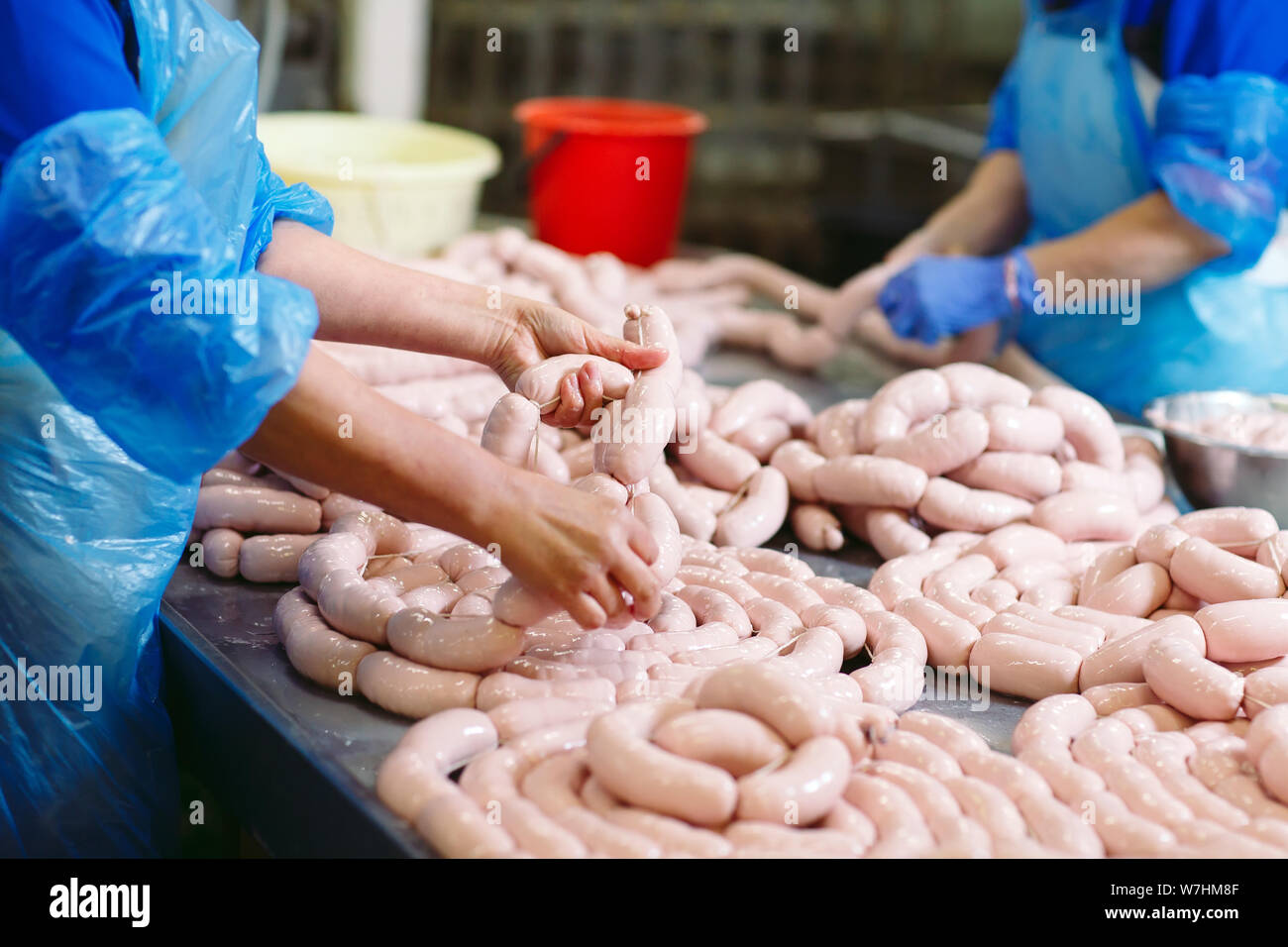 Butchers processing sausages at the meat factory. Stock Photo