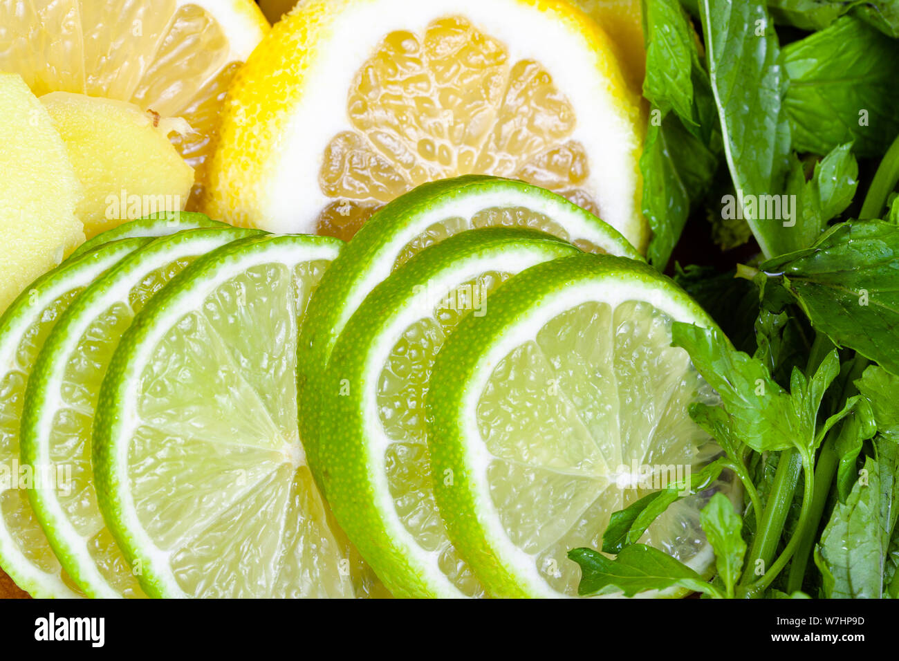 food background - cocktail ingredients, thin sliced fresh limes, lemons and ginger with green mint leaves close up Stock Photo