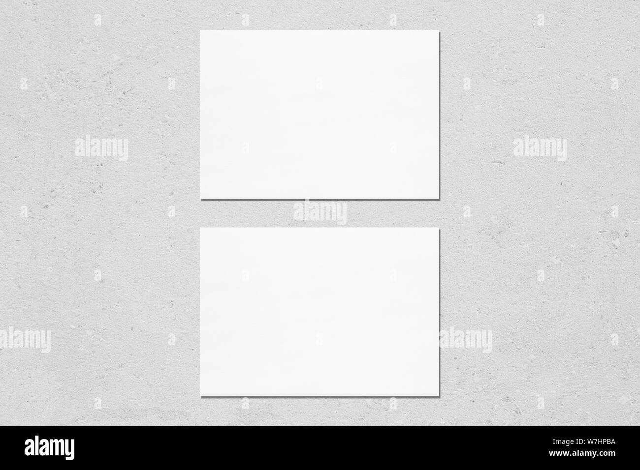 Two empty white horisontal rectangle a5 sized card mockups with soft shadows on neutral light grey concrete wall background. Flat lay, top view Stock Photo