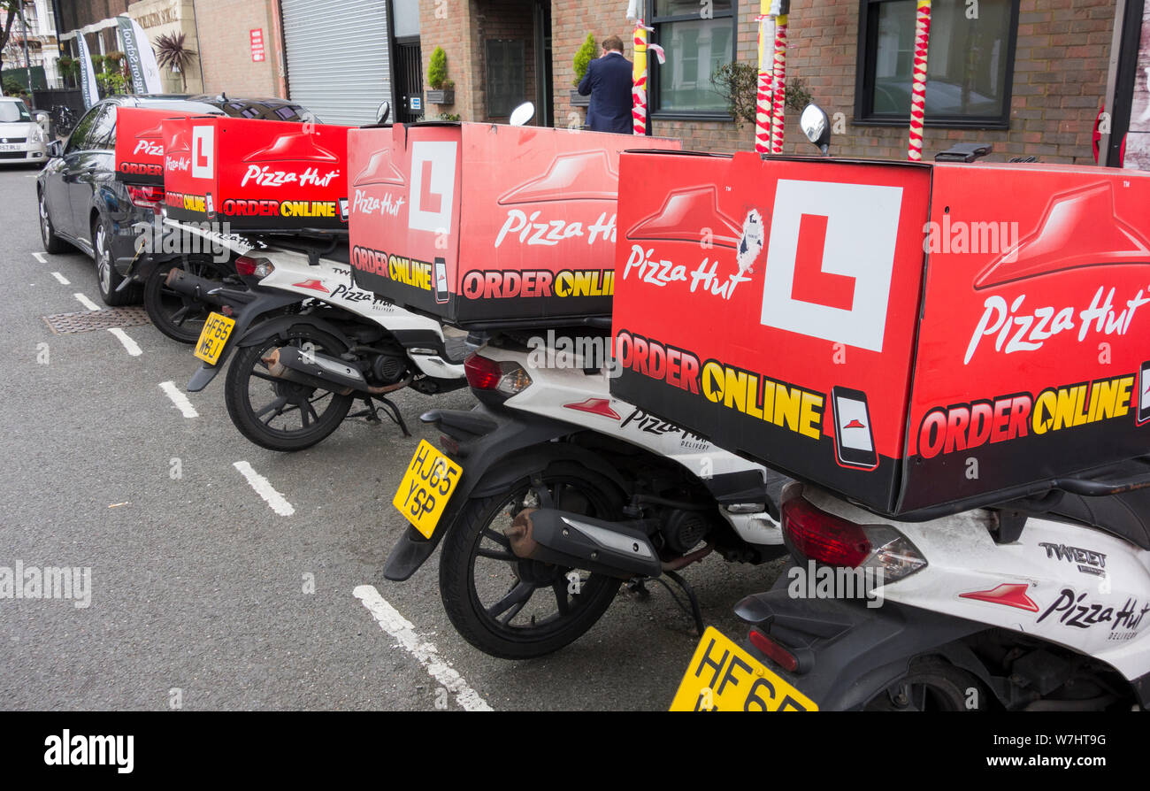 A row of PIzza Hut scooters parked outside one of its shops on Fulham Road, Fulham, London, UK Stock Photo