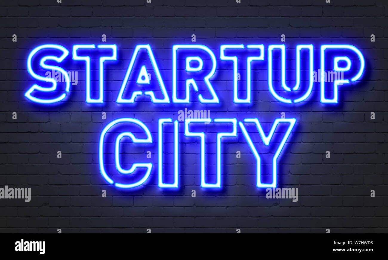 Startup city neon sign on brick wall background Stock Photo