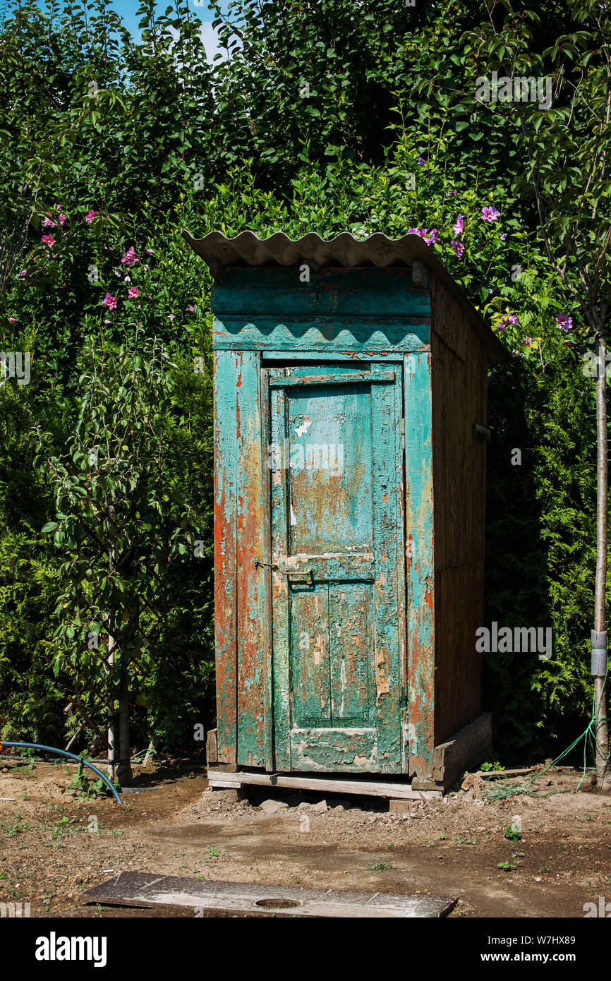 Rustic outdoor toilet stands in the garden sparkling, reflecting the