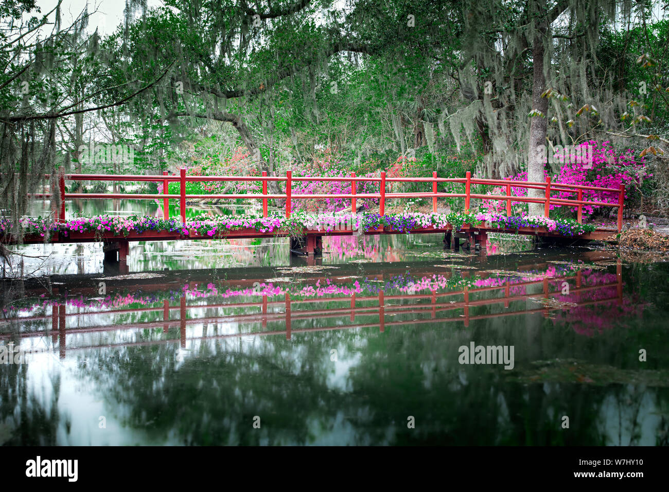 Red bridge with blooming flowers over still water in Charleston, South