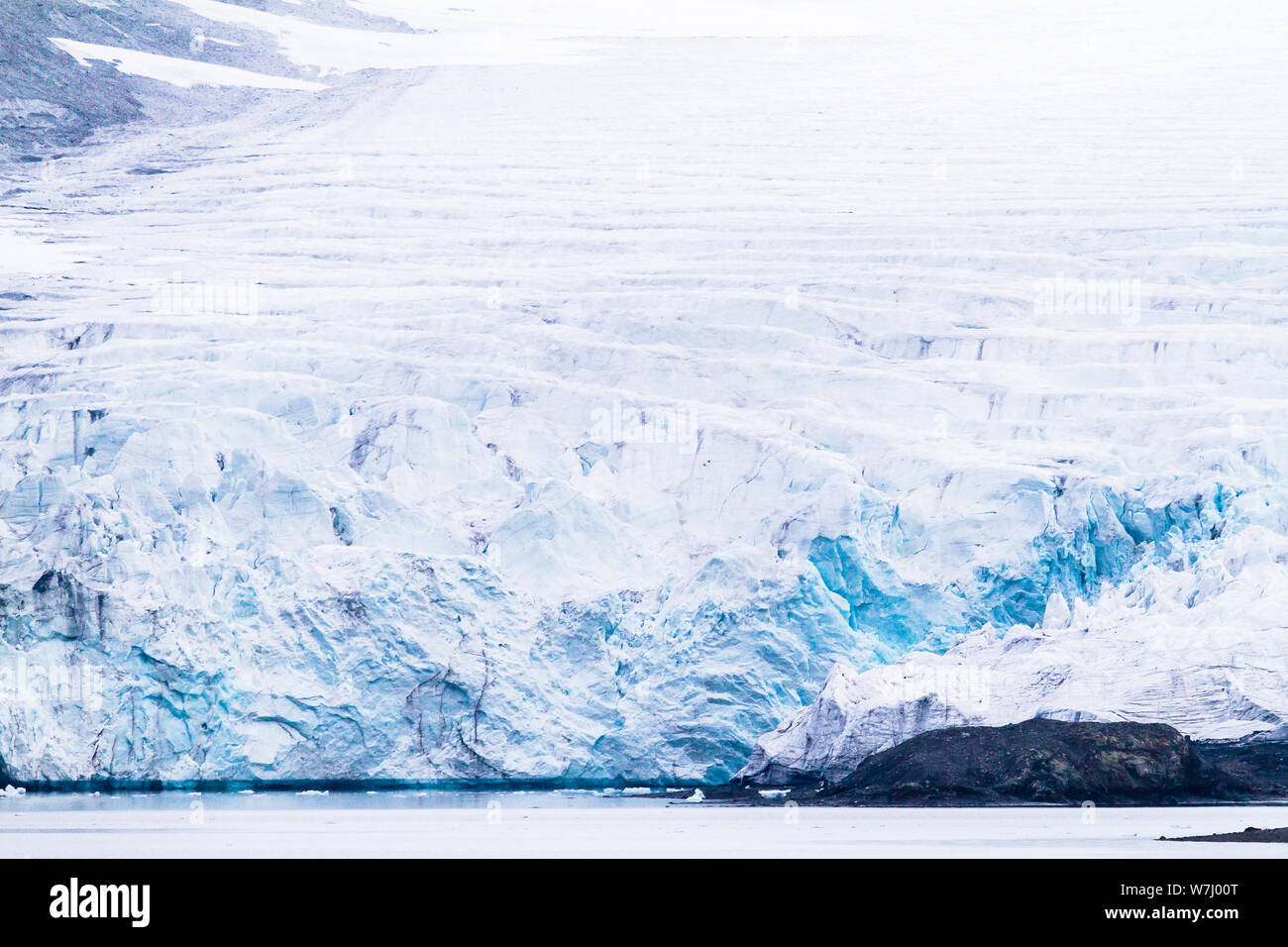 Repetitive rifts can be seen in a glacier descending to the sea in St Johnsfjorden / Prins Karls Forland in Svalbard.  These crevasses are caused by the constant movement of the glacier, causing tension between solid plates and the subsequent fracturing at weak points. Stock Photo