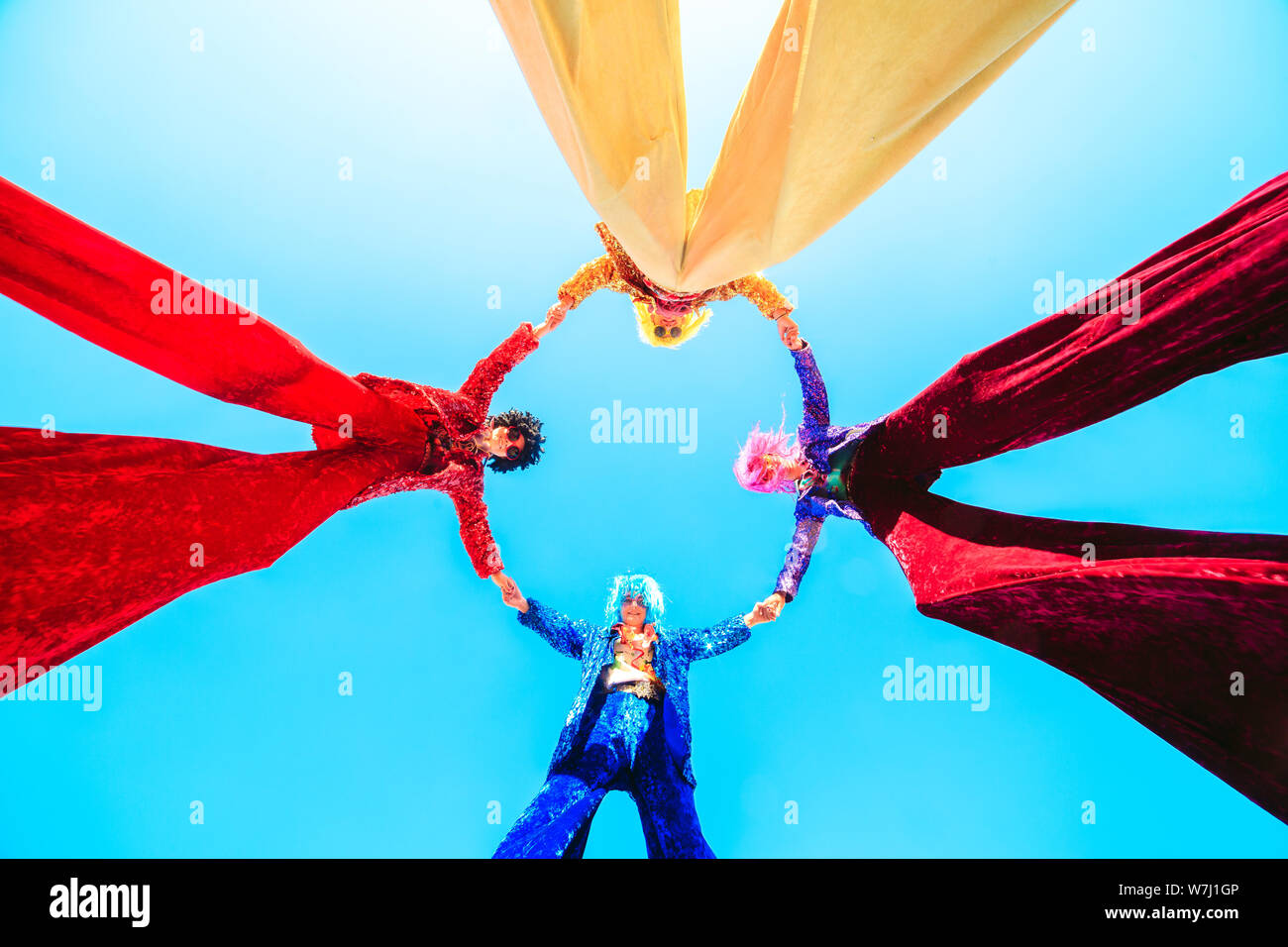 Young people on stilts posing against the blue sky Stock Photo - Alamy