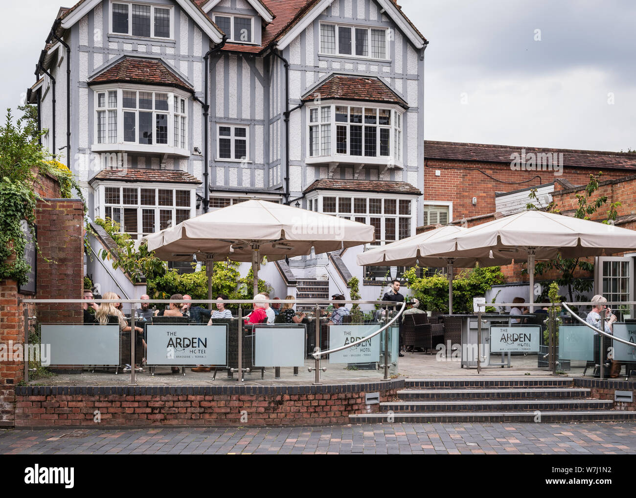 Cafes and restaurants. An exterior view of The Arden Hotel terrace with outside diners under sunshades. Stock Photo