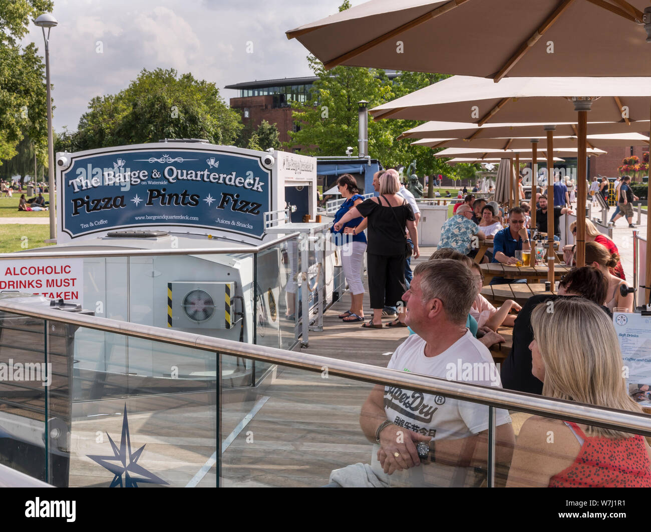 Cafes and restaurants. The Barge and Quarterdeck riverside bar and pizza place with outside diners under sunshades. Stock Photo