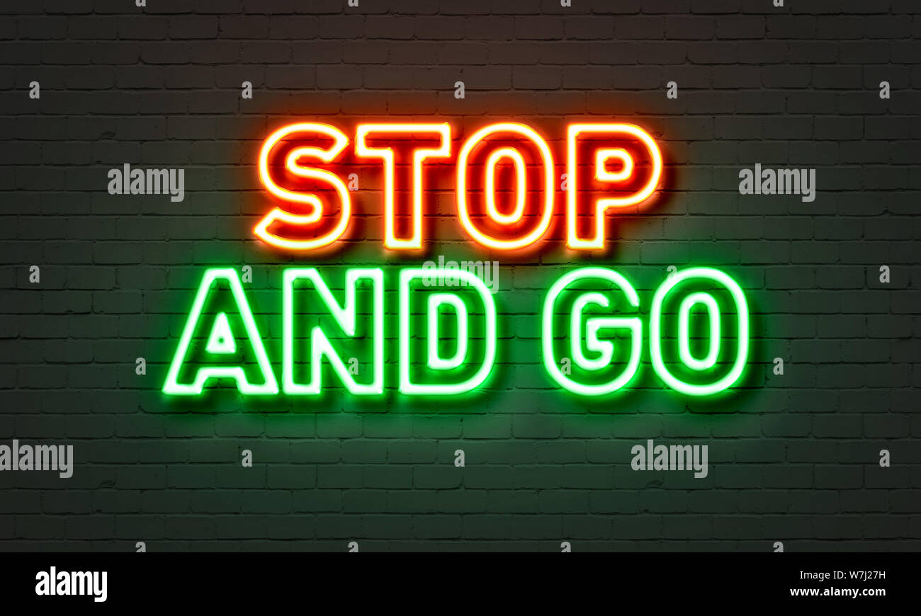 Stop and go neon sign on brick wall background Stock Photo - Alamy