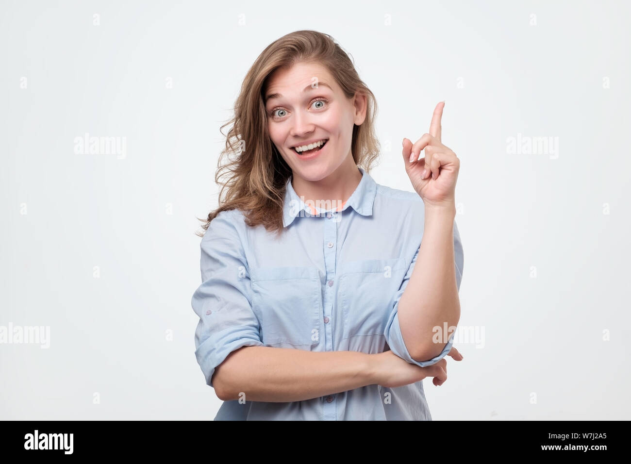 Cheerful young woman holding her index finger up Stock Photo
