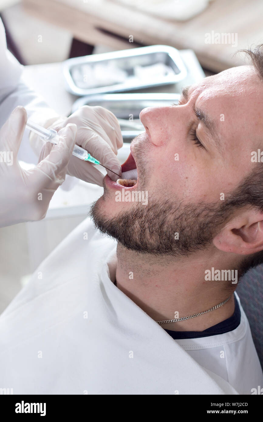 Dentist makes an injection with anesthesia in the gum of the patient. A