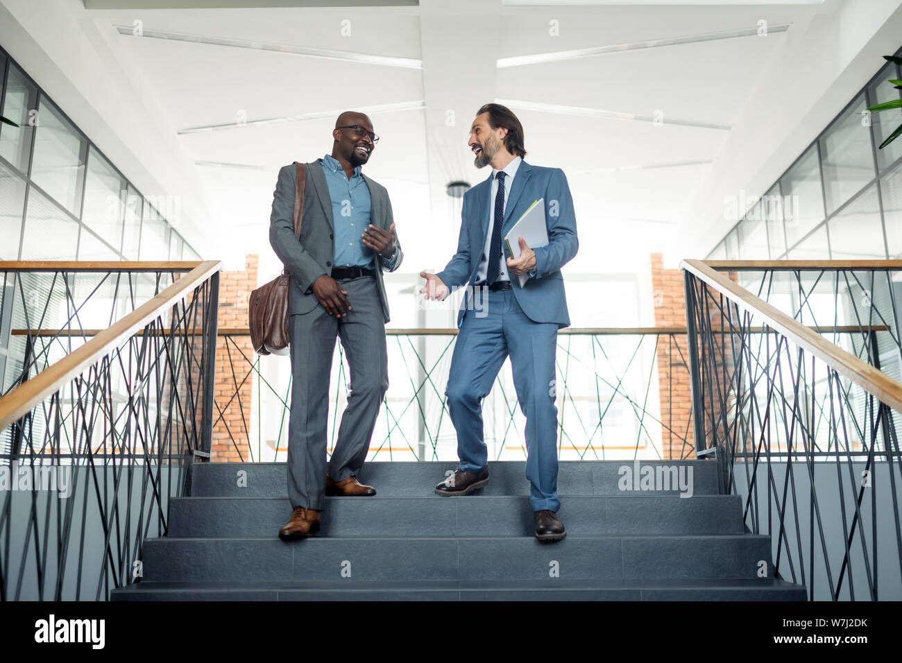 Two businessmen going down the stairs while having lunch break Stock Photo