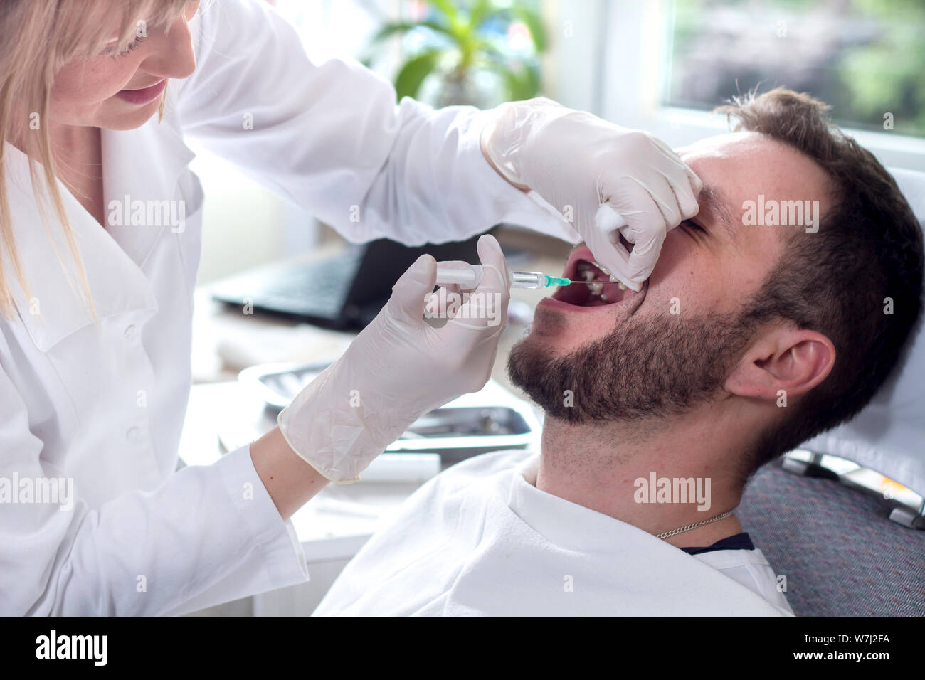 dentist makes an injection with anesthesia in the gum of the patient. A