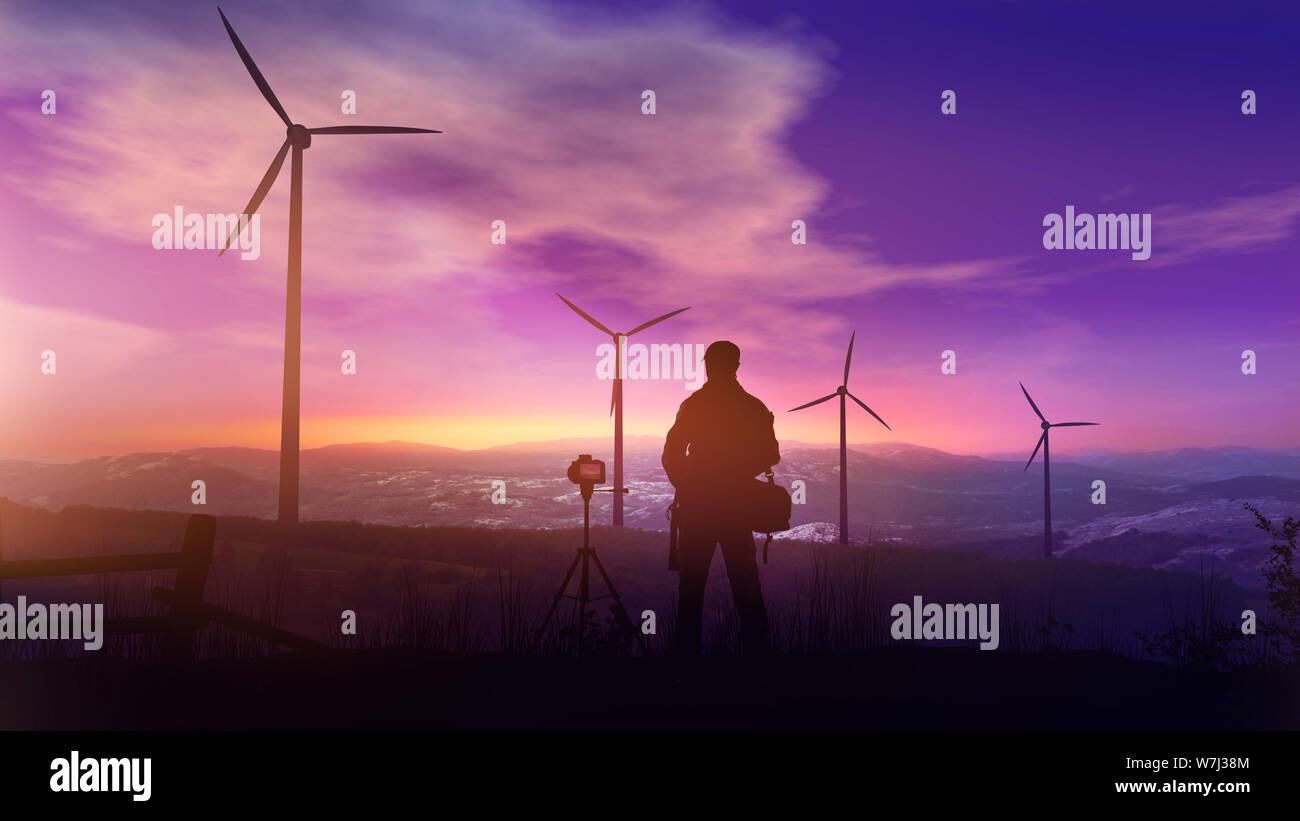 Photographer with a tripod photographs the landscape with wind turbines ...
