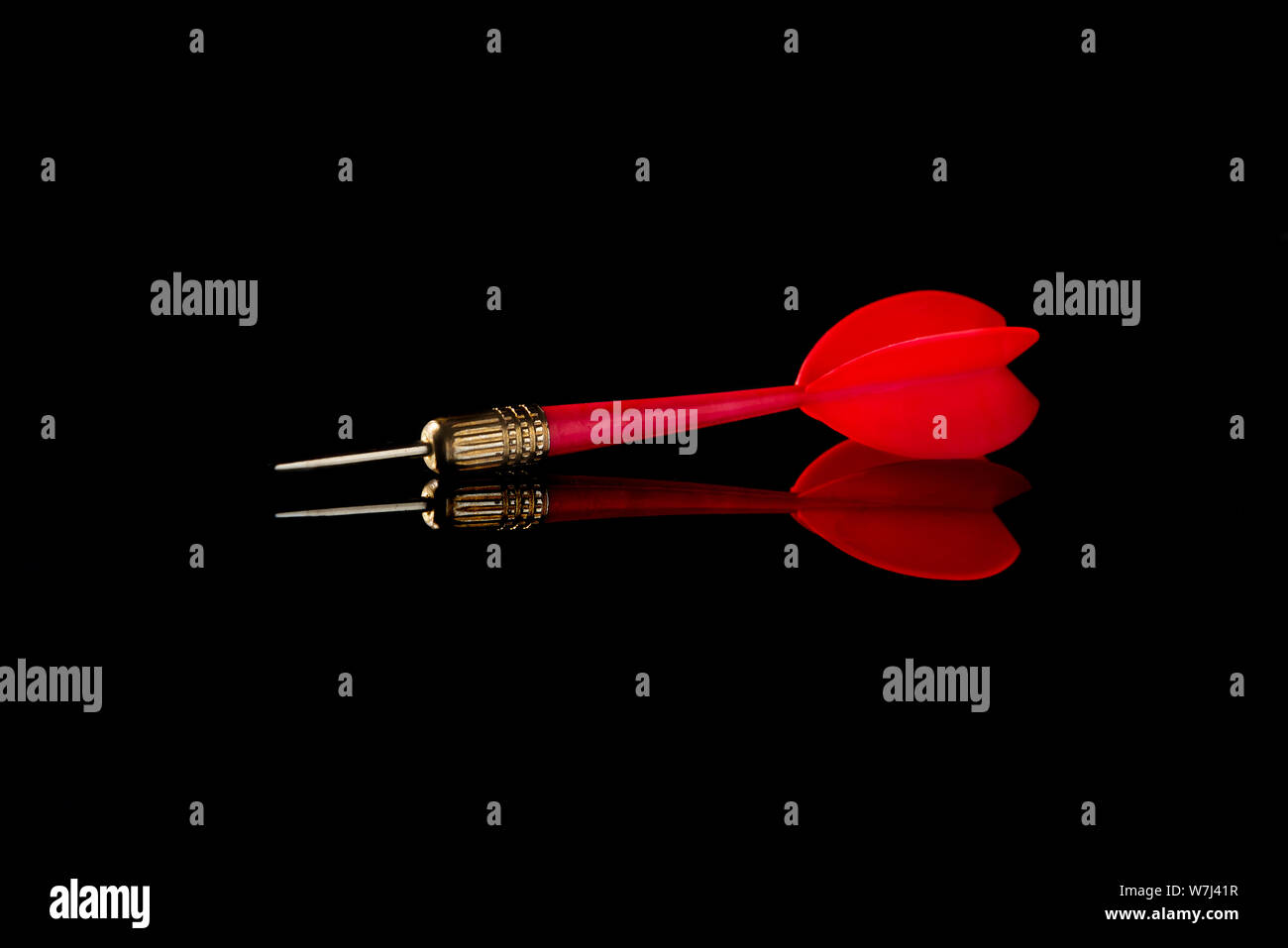 Red dart on a black background. Hit the target. Stock Photo