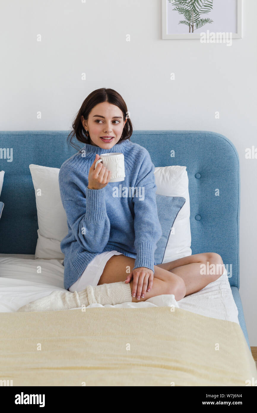 https://c8.alamy.com/comp/W7J6N4/girl-in-a-blue-sweater-in-hygge-style-interior-with-a-cup-of-hot-tea-her-hand-sits-on-the-bed-W7J6N4.jpg