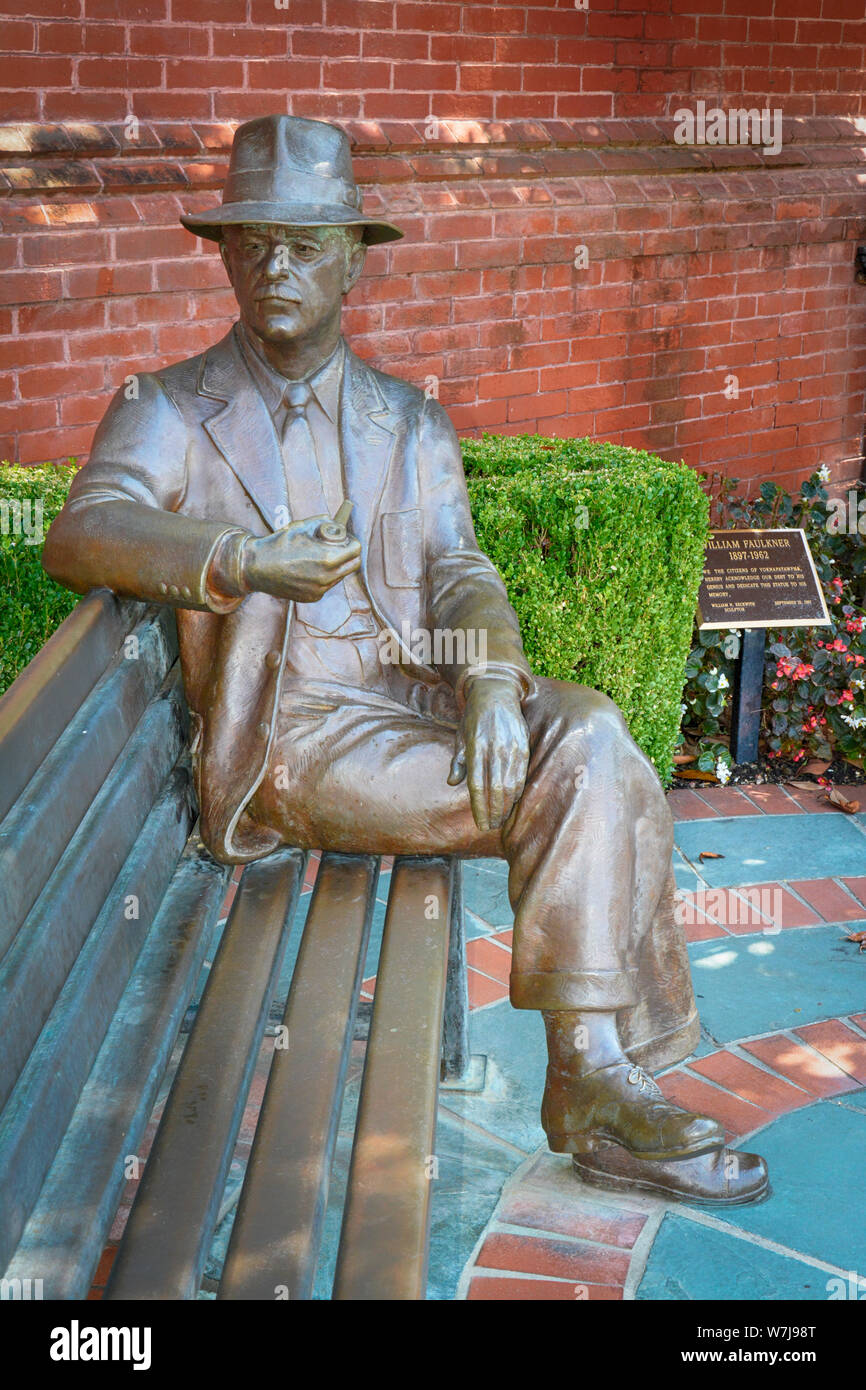 Bronze plaque and statue of William Faulkner seated on a bench with hat and pipe near City Hall in his hometown of Oxford, MS, USA Stock Photo
