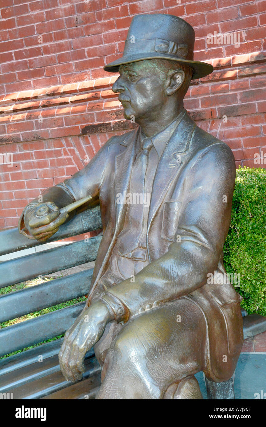 Bronze statue of William Faulkner seated on a bench with hat and pipe near City Hall in his hometown of Oxford, MS, Stock Photo