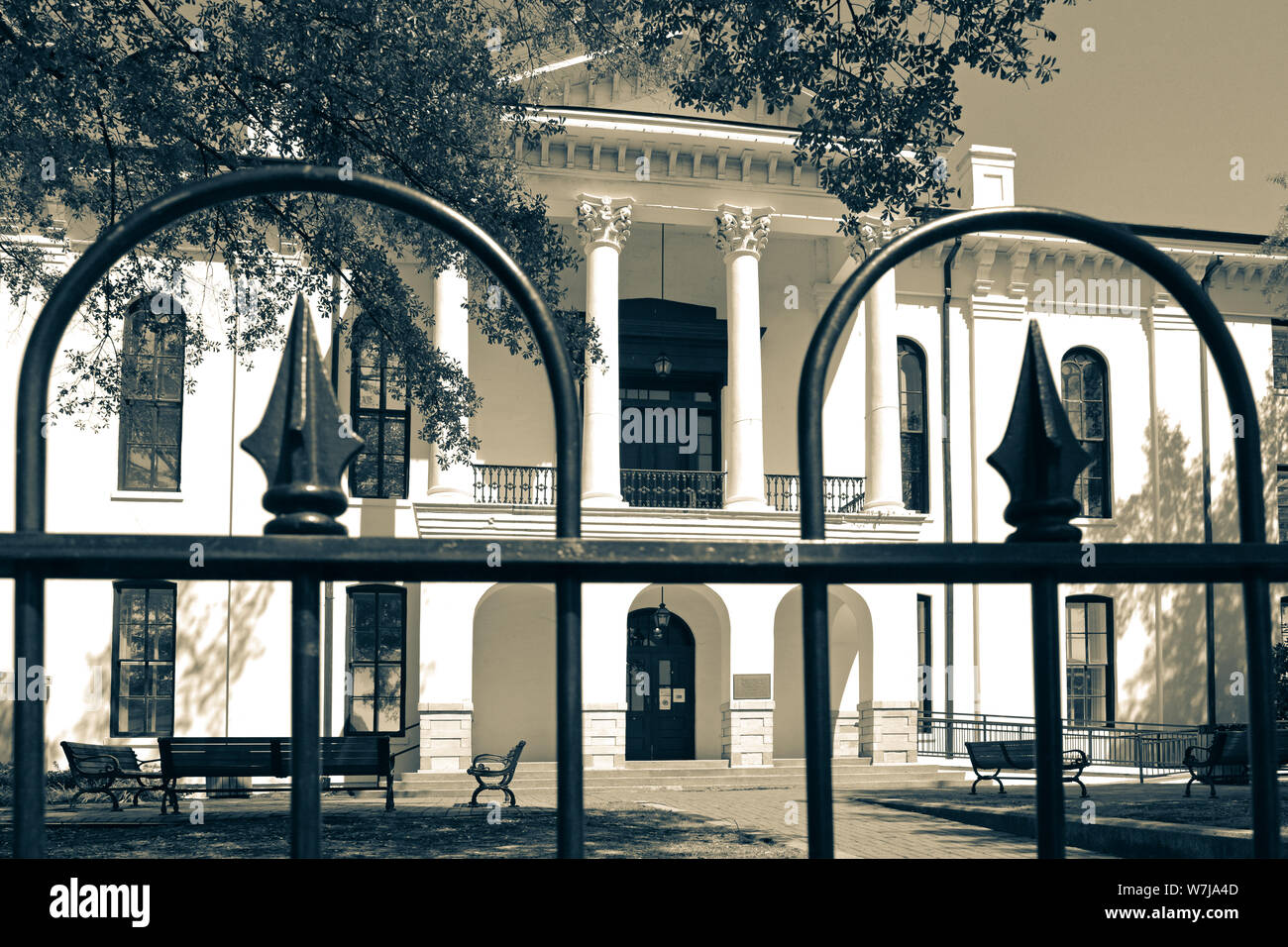 The historical Lafayette County Courthouse in Greek Revival style as seen through wrought iron fence, on the courthouse square in Oxford, MS, in sepia Stock Photo