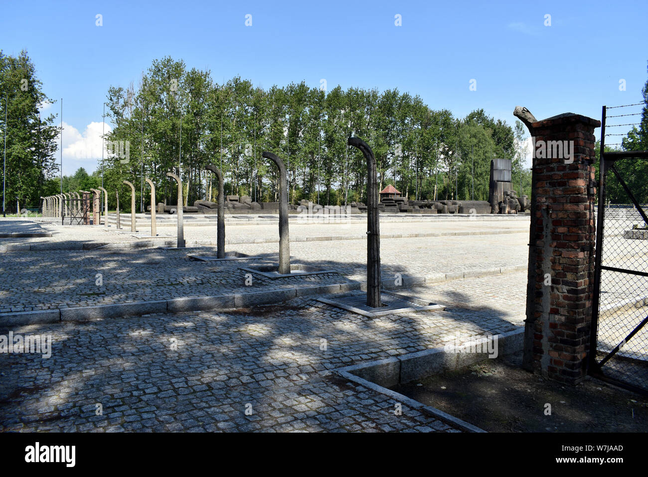 Birkenau/Poland-June 3, 2019: A distant view of the International Memorial taken through the remains of an electrified fence at the Birkenau Concentra Stock Photo