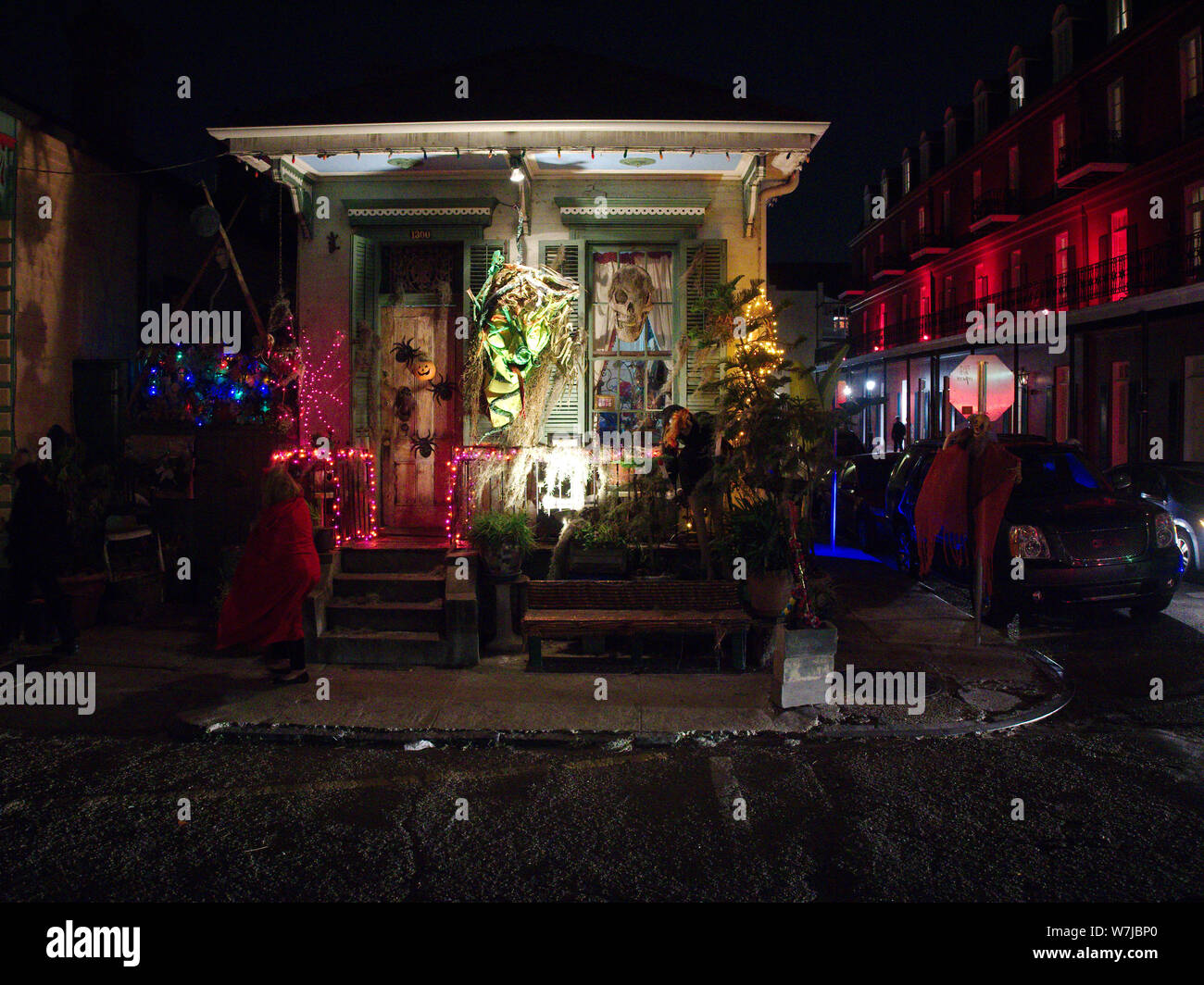 New Orleans, Louisiana, USA - October 31, 2018: A woman wearing a costume walks in front of a decorated house on Halloween night. Stock Photo
