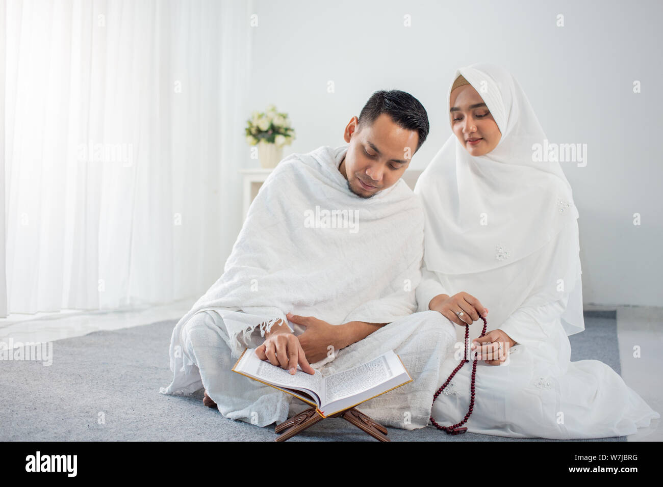 asian wife and husband praying with AlQur'an and tasbih Stock Photo